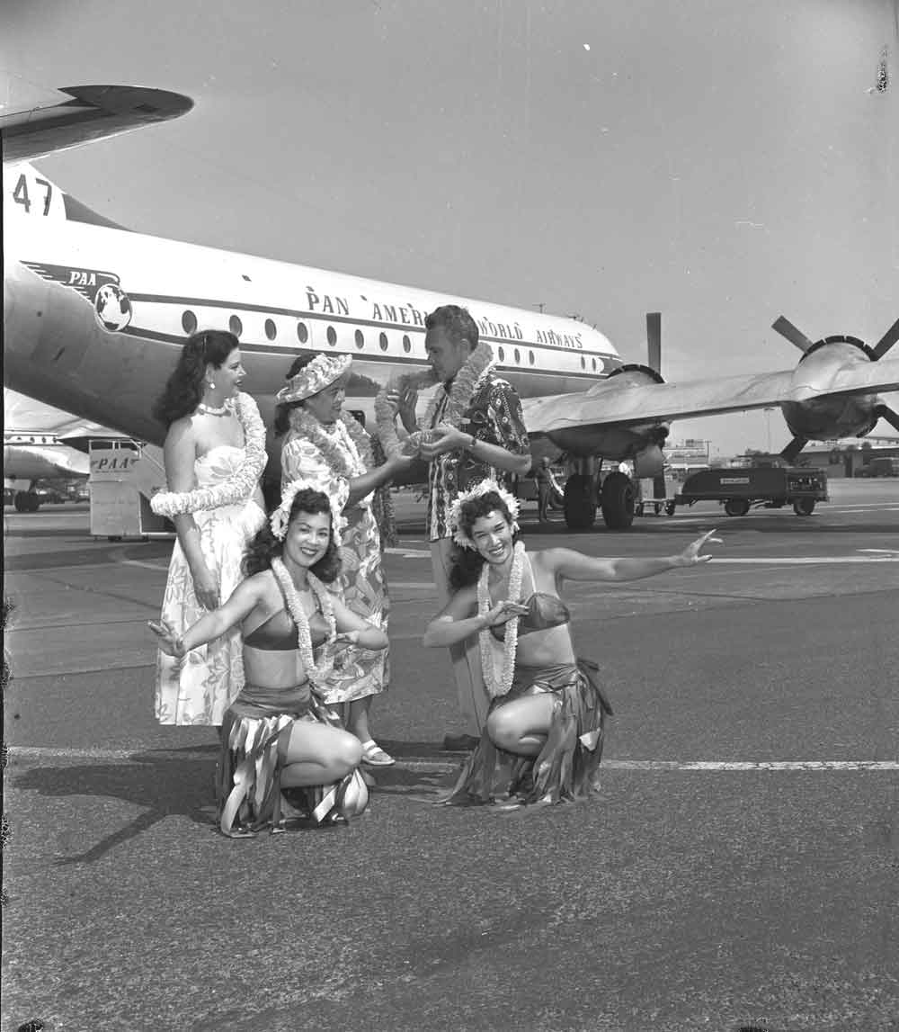 1954 Hula girls with a Pan Am Beoing 377 Stratocruiser in the background.